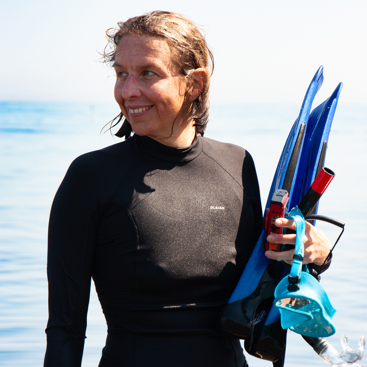 Photo of a woman looking out to sea holding snorkelling gear in Britain